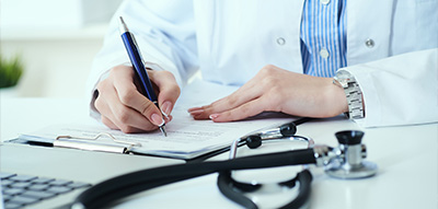 Doctor writing notes on a clipboard with a stethoscope next to them