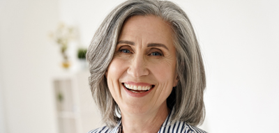 Older woman with grey hair smiling at camera
