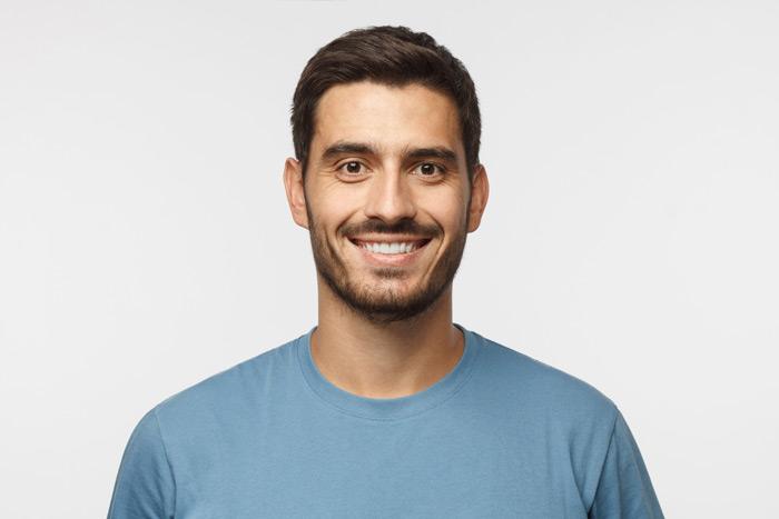 Male smiling infront of a white background